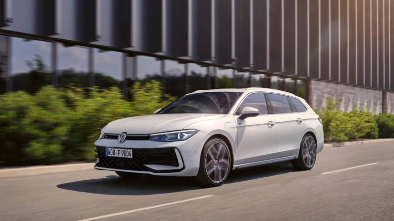 A sleek white Volkswagen Passat drives on a sunlit road beside a modern glass building. The scene feels dynamic and modern, with a focus on style.