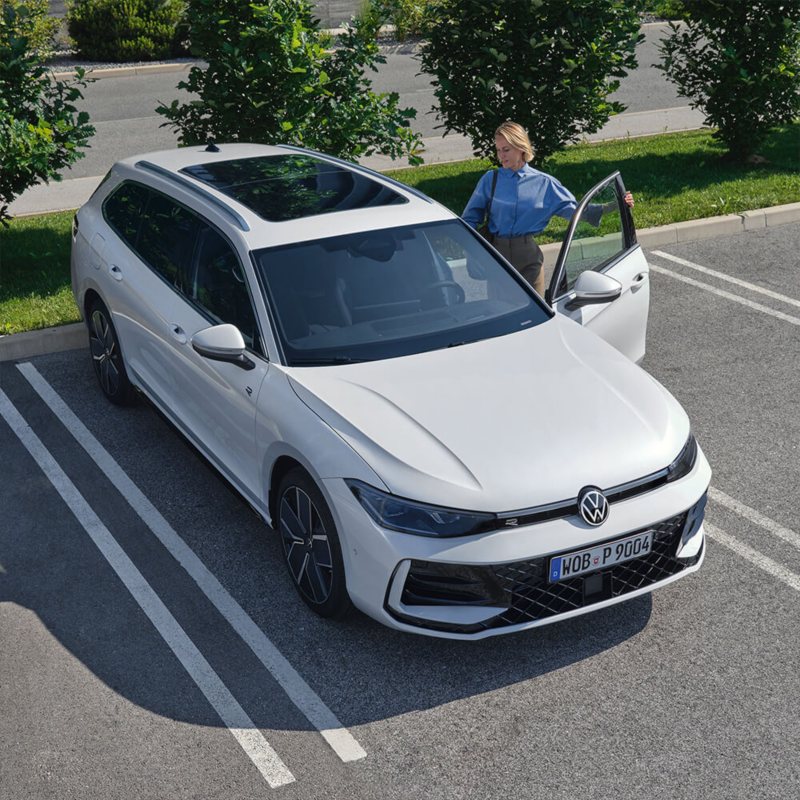 Nouvelle Passat blanche stationnée sur une place de parking avec une femme qui entre dans le véhicule.