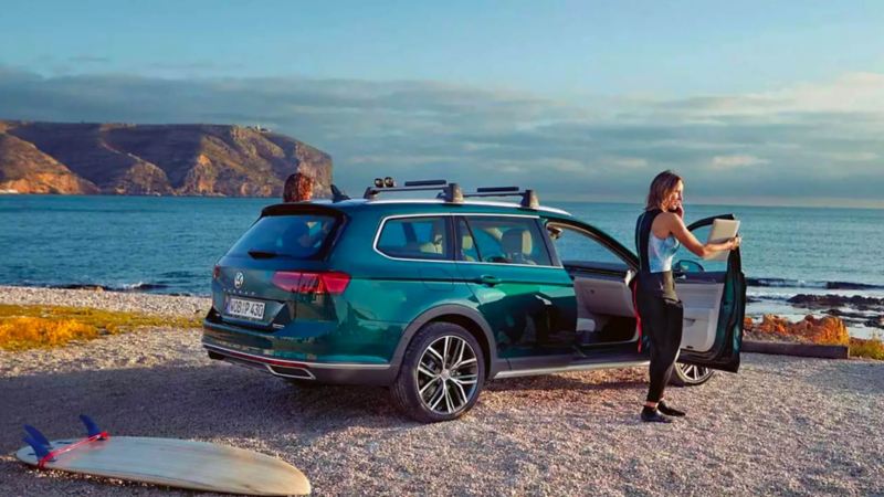Passat alltrack garée sur la plage avec une planche de surf à l'arrière