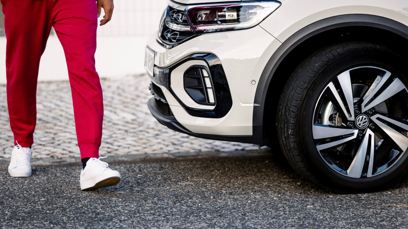A man walking beside a white VW car