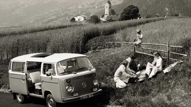 En familj har picknick i naturen bredvid sin VW folkabuss