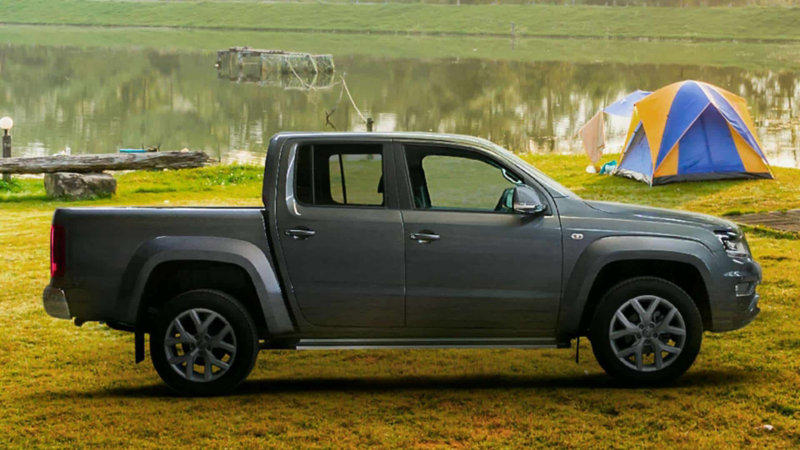 Volkswagen Amarok Highline cerca de un lago en espacio boscoso. 