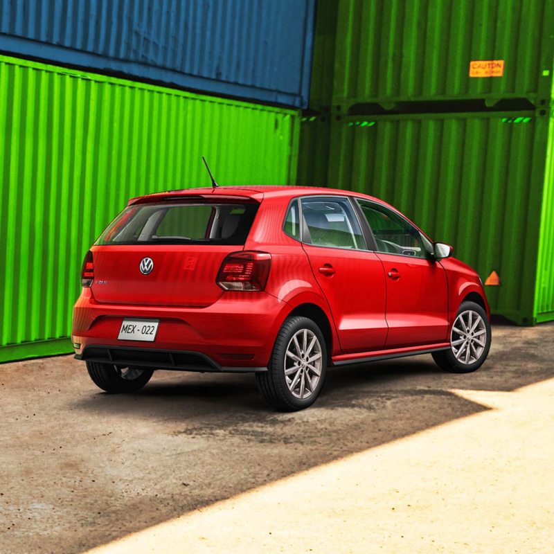 Volkswagen Polo seminuevo de color rojo cerca de contenedores industriales. 