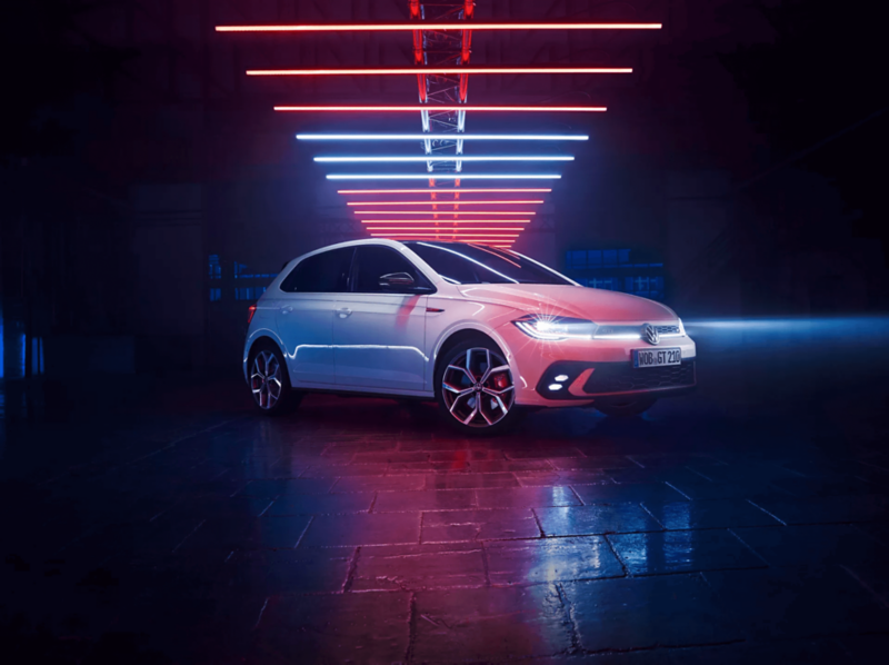 Photo showing a white VW Polo against a neon studio background. 