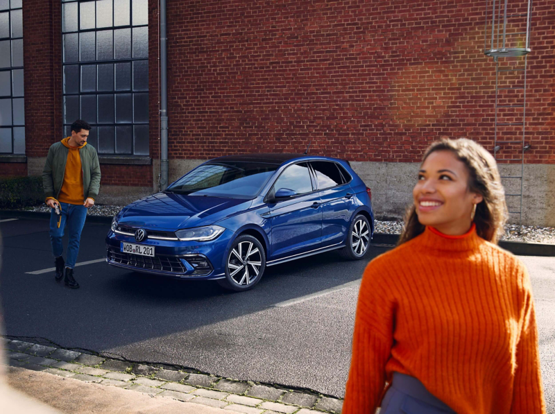 A woman standing in front of a Volkswagen Polo