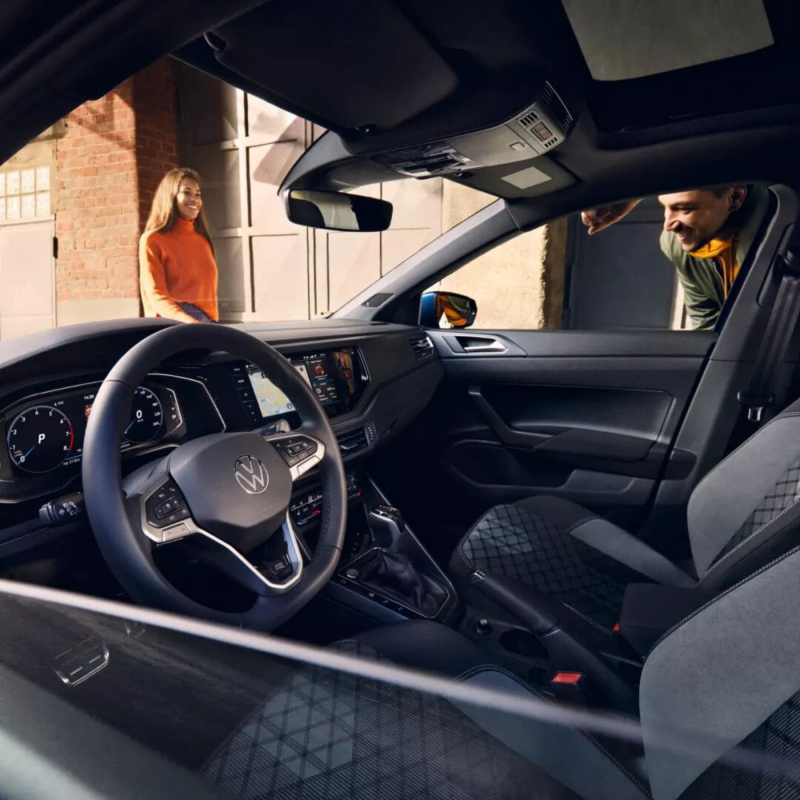 Interieur van de Volkswagen Polo en een man kijkt van buiten naar binnen