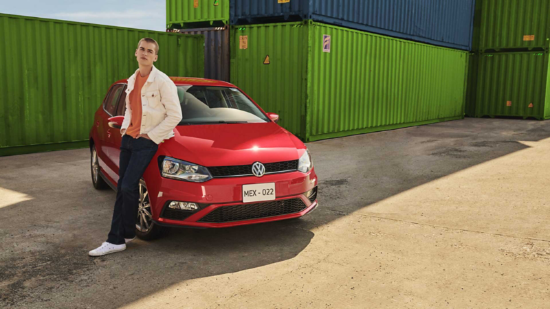 Polo 2021 Comfortline en color rojo, estacionado cerca de contenedores. 