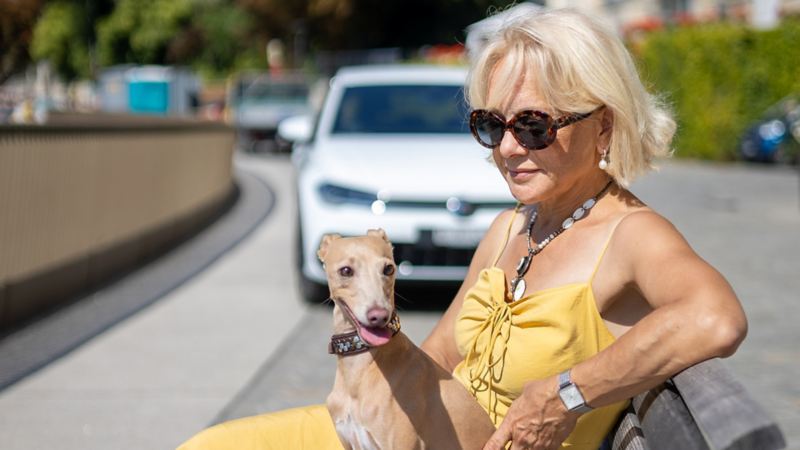 Marilena Bachmann sitzt auf einer Bank mit ihrem Hund Limbo und der neue Polo ist hinter ihnen parkiert