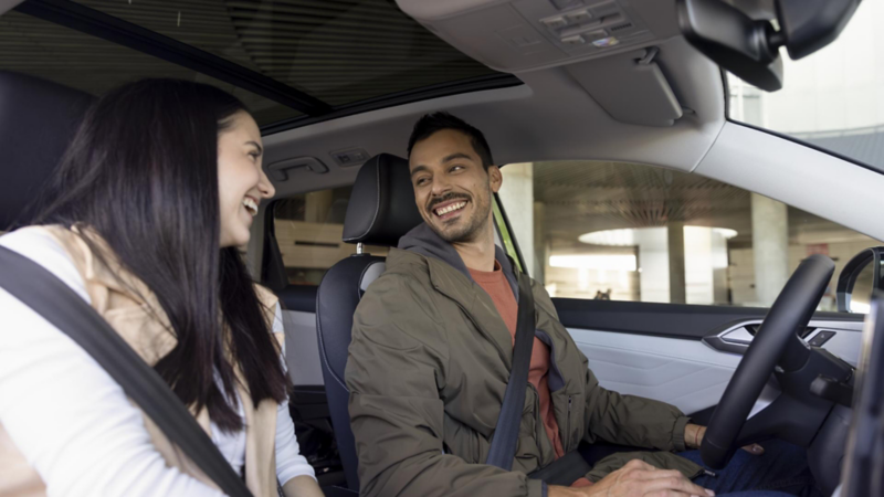 Pareja sonríe dentro de un auto Volkswagen.