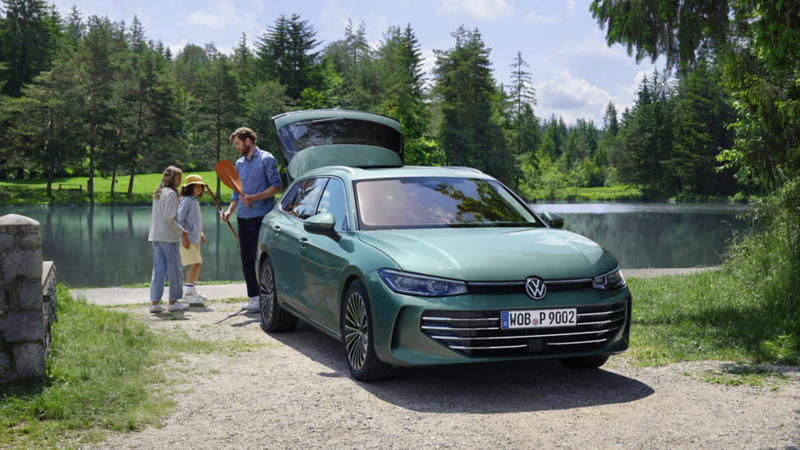 Un homme et ses enfants sont derrière une VW Passat garée devant une rivière.