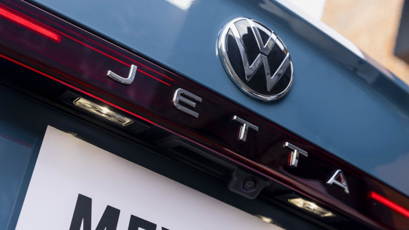 Emblema VW, nombre de modelo Jetta y línea de luz LED en la parte trasera del auto sedán. 
