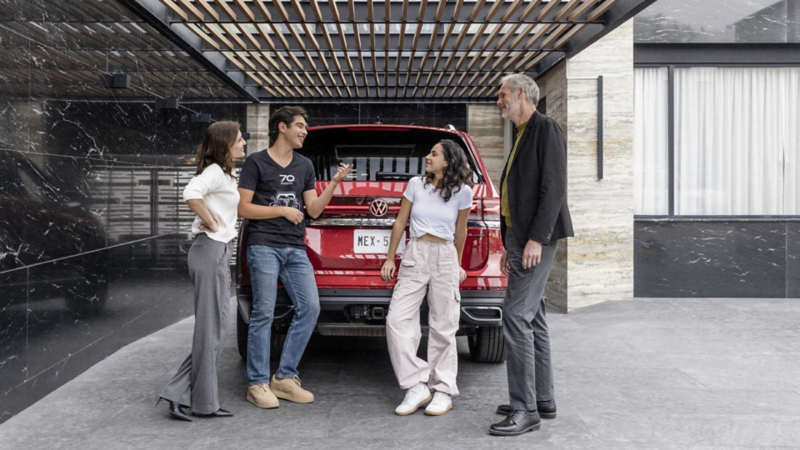 Familia convive cerca de una camioneta Teramont 2025 de color rojo.