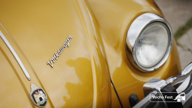 Faro y logo de Volkswagen en el cofre de un Vocho antiguo color mostaza.