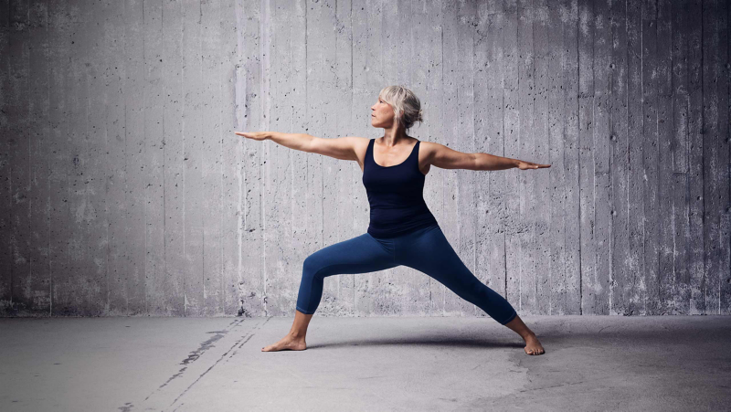 Kvinna gör Yoga mot en grå bakgrund