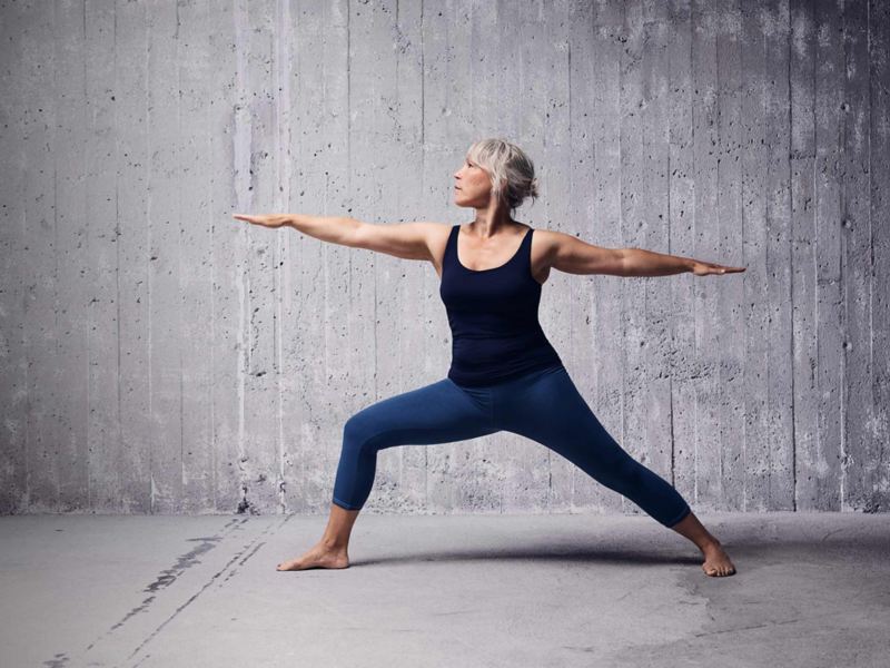 Kvinna gör Yoga mot en grå bakgrund