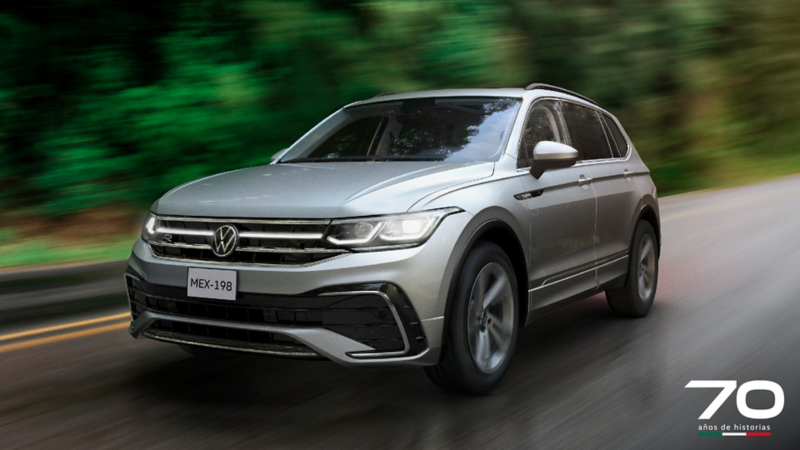 Volkswagen Tiguan 2024 circula en medio de una carretera boscosa.