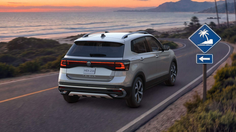 SUV Taigun. Vista trasera de camioneta de color gris en carretera costera,  con señalamientos de playa cercana. 