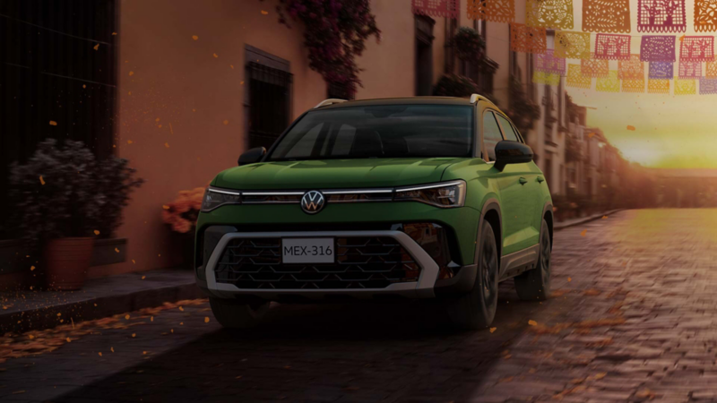 SUV Taos verde en vista frontal de tres cuartos sobre una calle empedrada al atardecer.