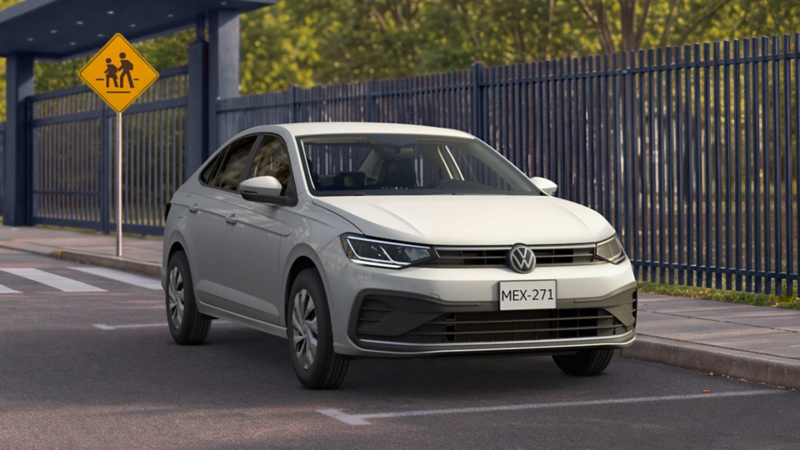 Volkswagen Virtus color blanco circula sobre una calle cercano a una banqueta. 