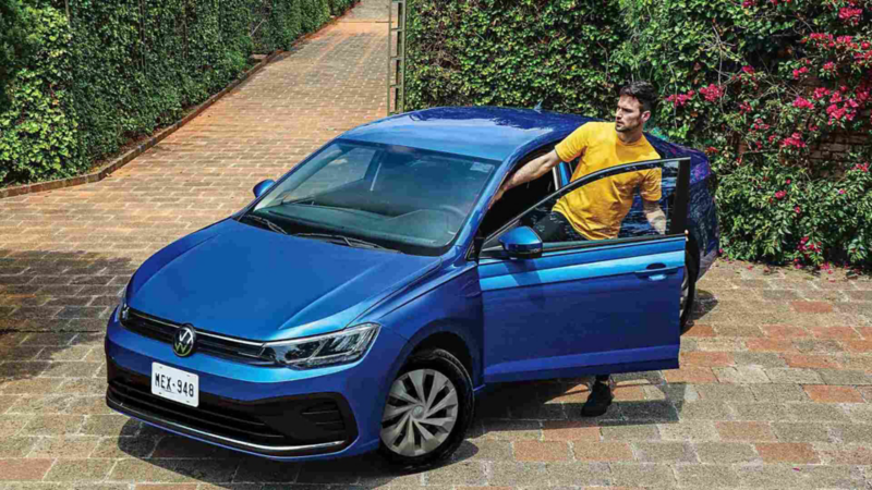 Auto sedán 2023 Virtus de Volkswagen, en color azul, sobre camino de ladrillos. 