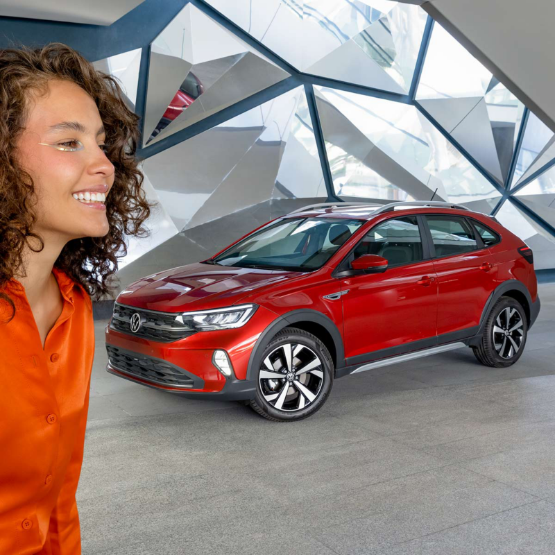 Nivus de Volkswagen en color rojo con joven mujer sonriente que usa blusa naranja. 