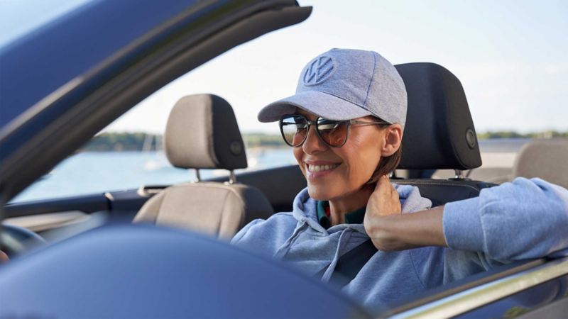Primo piano di una donna sorridente mentre è alla guida di una vettura Volkswagen.