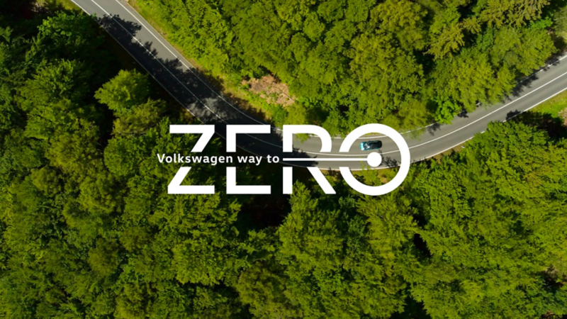 Napis „Volkswagen Way to Zero” na tle lotniczego widoku lasu.