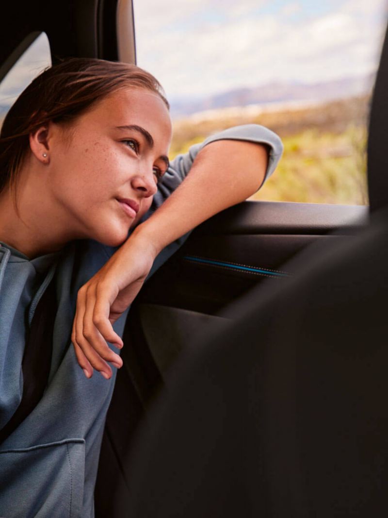 Une jeune fille regarde par la fenêtre arrière d'une Volkswagen ID.7.