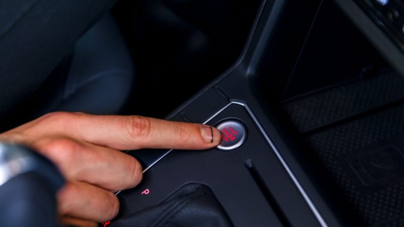 Dedo de conductor oprime botón Push To start ubicado en el panel central de un Volkswagen.