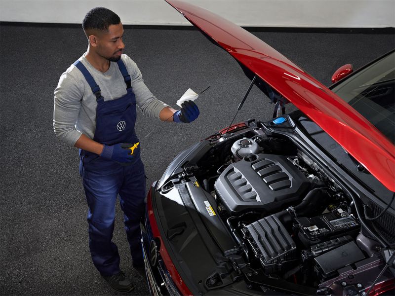 A service employee checks something in the cockpit of a VW