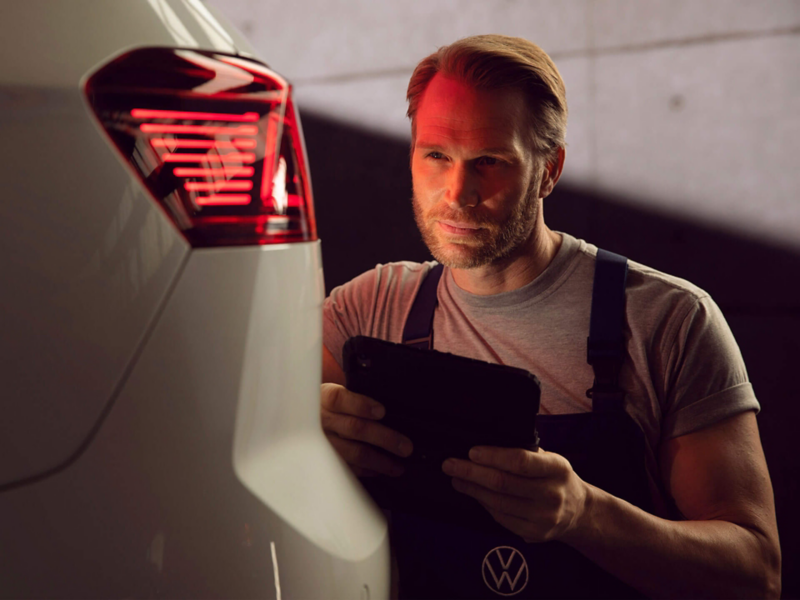 Un technicien Volkswagen inspecte l'arrière d'une voiture lors de l'entretien.