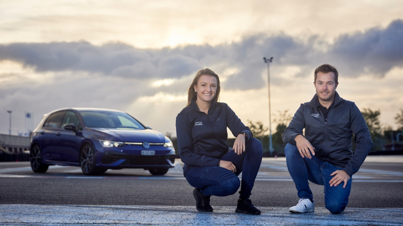 Jasmin Preisig und Benjamin Leuchter posieren vor dem Golf R auf der L'Anneau du Rhin Strecke