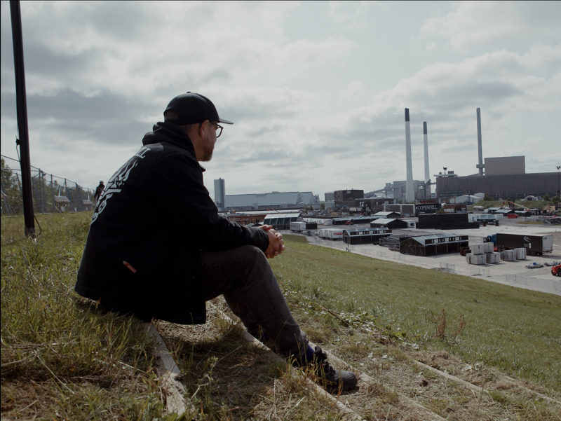 Mand som sidder på en bakke og kigger ud over COPENHELL.