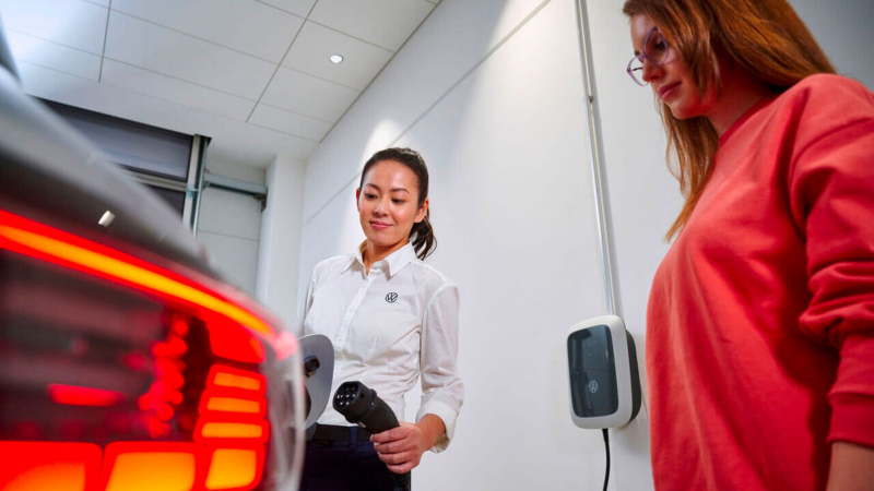 Une technicienne Volkswagen et une cliente s'apprêtent à brancher la prise d'une Volkswagen ID.