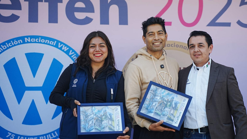 Directivos de Volkswagen México sostienen cuadros conmemorativos en evento Treffen.