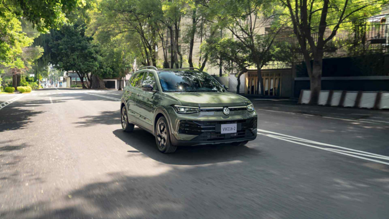 Volkswagen Taigun verde circula de frente por una avenida arbolada y despejada.