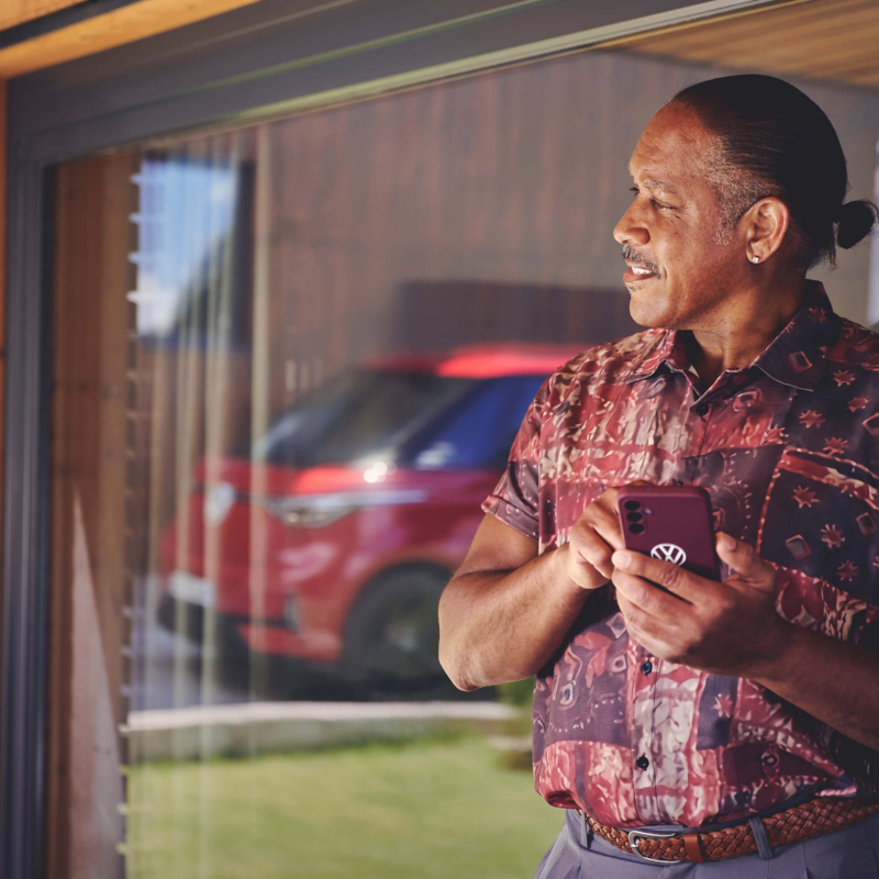 a man looking at a VW vehicle holding a VW branded mobile phone