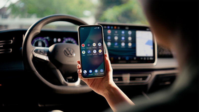Una mano sujetando un móvil en el interior de un Volkswagen