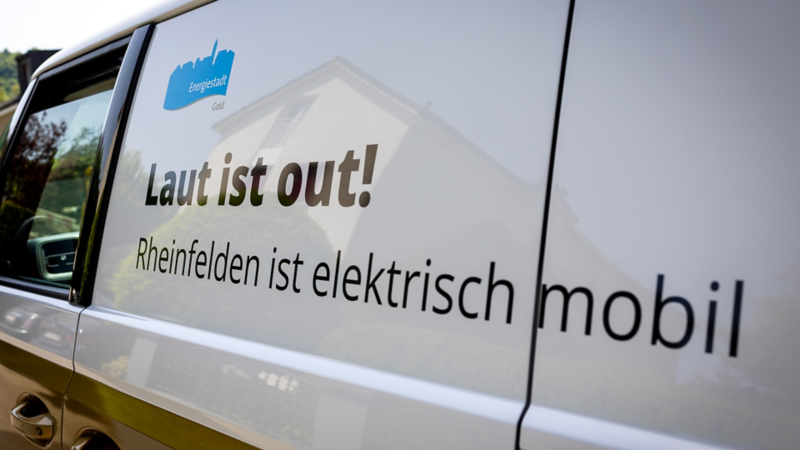Seitliche Fahrzeugansicht mit dem Aufdruck ‚Laut ist out! Rheinfelden ist elektrisch mobil‘ sowie dem Logo der Energiestadt.