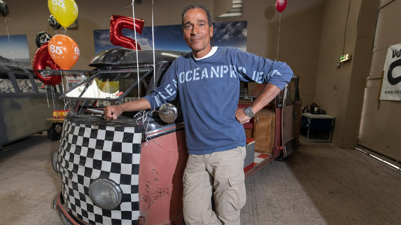 Riki standing next to his VW Samba van.