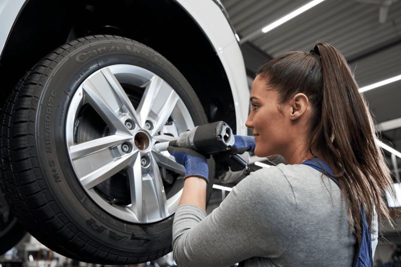 Kobieta zmienia koło w samochodzie marki Volkswagen.