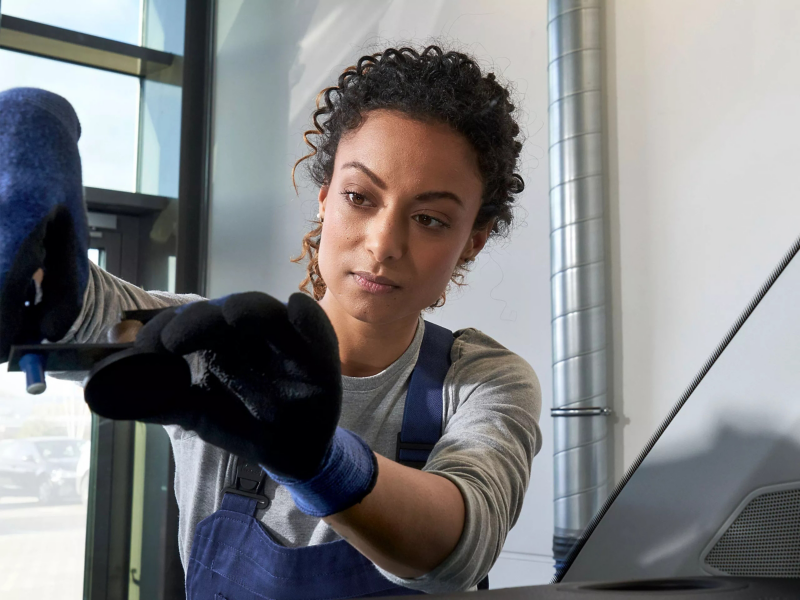 Volkswagen servicemedewerker laat iets zien aan klant op tablet, ze staan buiten een dealer locatie naast een ID. model