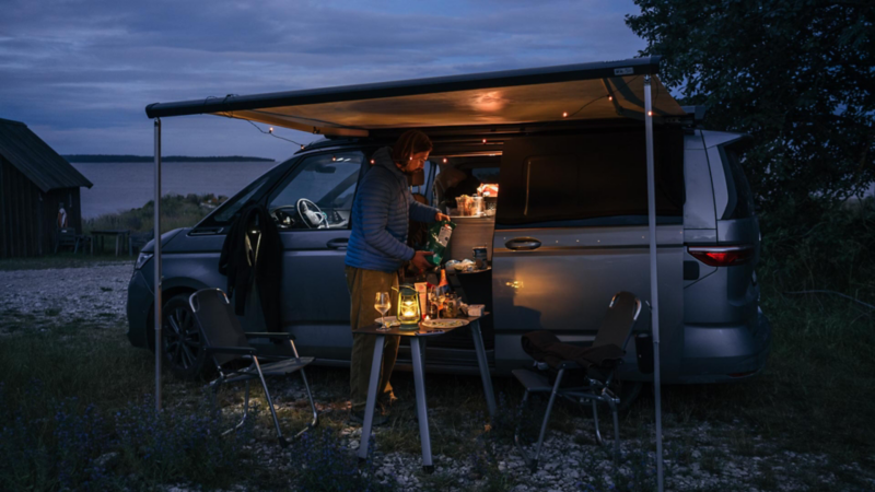 Sebastian lagar mat utanför VW California husbil på kvällen.