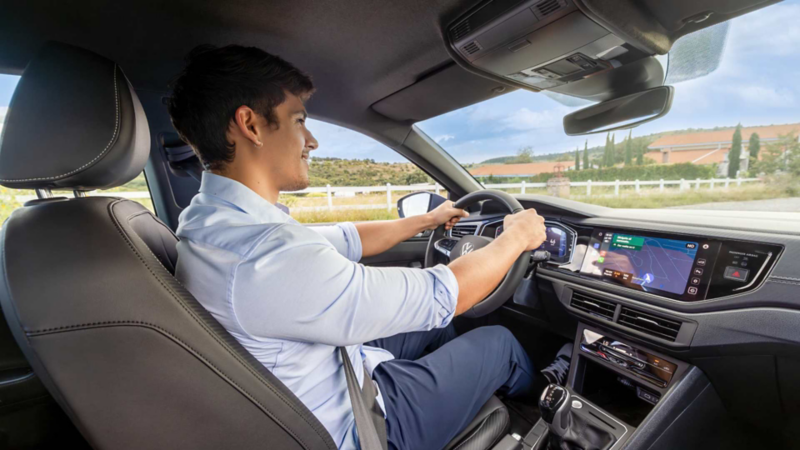 Joven conduce camioneta SUV de Volkswagen mientras sonríe.