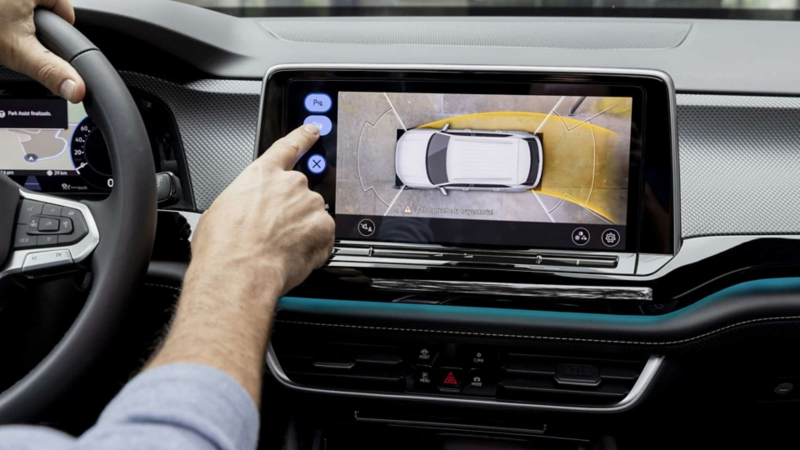 Conductor de camioneta Volkswagen toca la pantalla de su vehículo con vista a cámara 360.