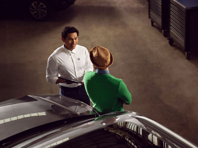 Pracownik serwisu Volkswagena odbiera samochód i rozmawia z klientem