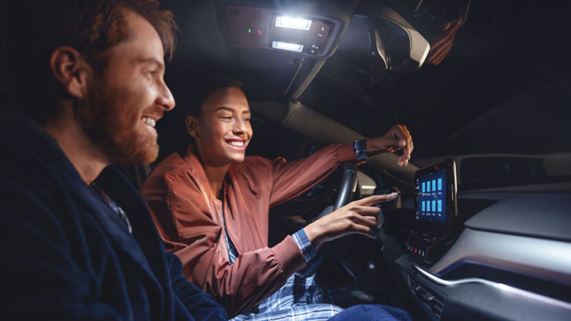 Un couple est assis ensemble dans la voiture et utilise le système multimédia.