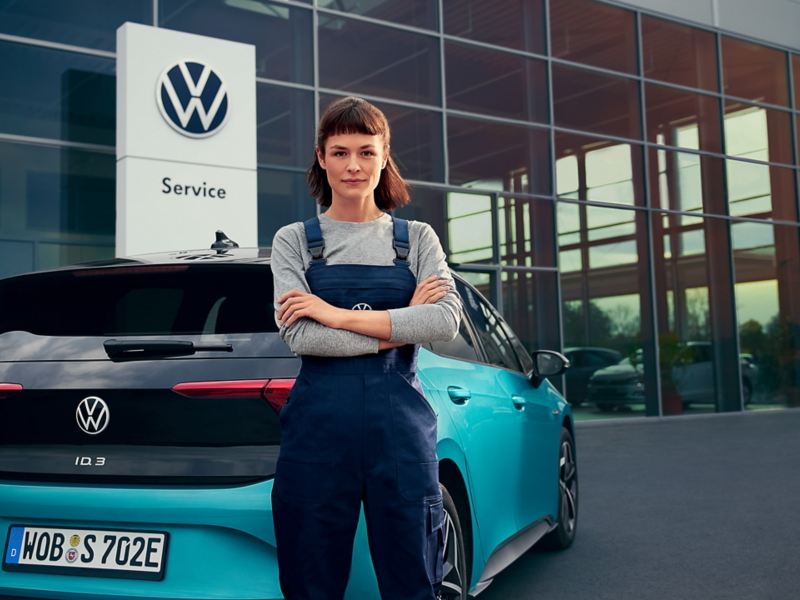 Une collaboratrice du service entretien VW se tient devant une VW ID.3.