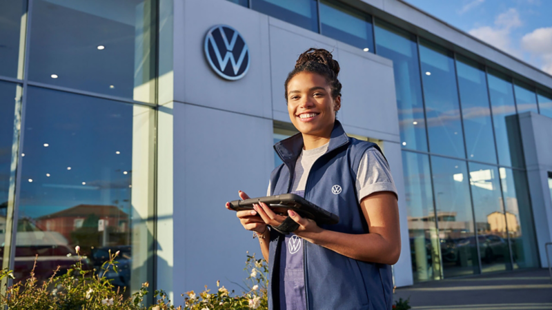 A Volkswagen mechanic standing outside of a Volkswagen service centre andholding an iPad