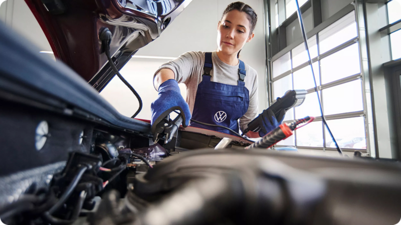 An engineer looking at an engine inside an open bonnet and interacting with it.
